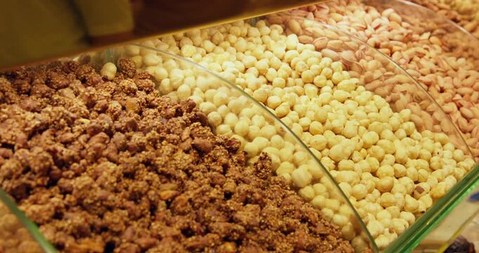 Close up of multiple breakfast cereals, granola, puffed grains stored in clear glass containers at food market or bulk bin display.