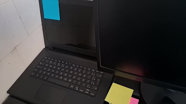Modern black laptop and desktop monitor motion setup with sticky notes