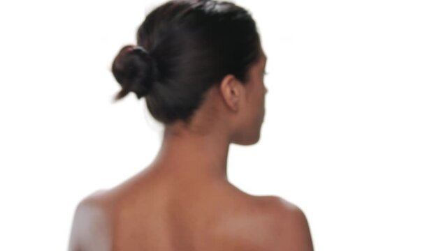Close up of young confident beauty model looking over shoulder turns and walks away showcasing her soft skin against white background | Skin softener commercial concept
