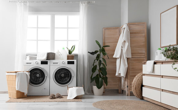 Interior of laundry room with wicker baskets, washing machines and folding screen