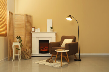 Obraz premium Interior of living room with glowing lamp, armchair and fireplace