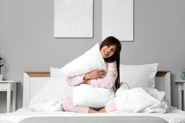 Morning of beautiful young woman hugging pillow in bedroom