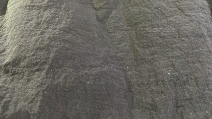 Naklejka premium A black fabric with a crinkled texture and a matte finish, featuring natural fold patterns and fine fiber details. Suitable for use as a background.