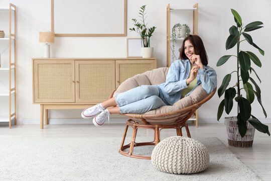 Young woman resting in cocoon chair at home