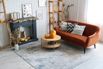 Obraz premium Stylish living room with fireplace, coffee table, sofa and pumpkins. Autumn concept