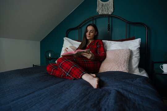 Woman reading a book while relaxing in bed
