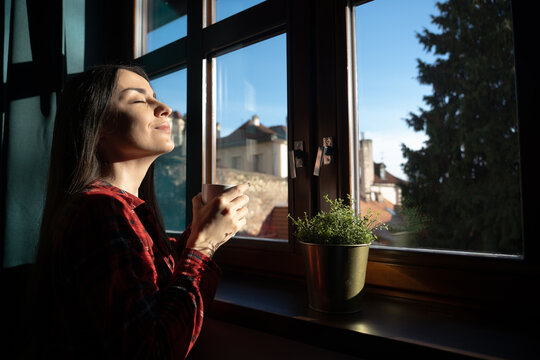 Woman enjoying morning sunlight with a warm drink