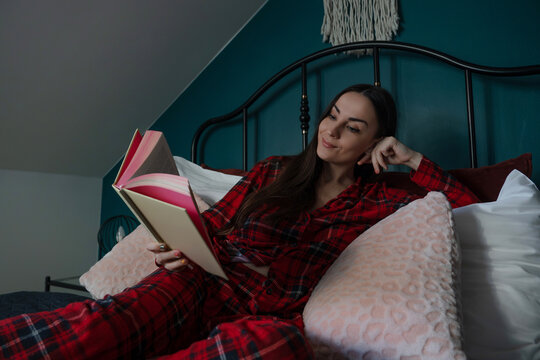 Relaxed woman reading a book while reclining in bed