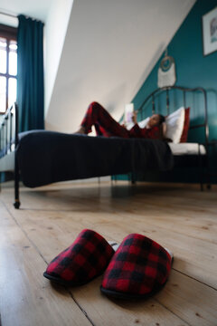Plaid slippers with woman reading on bed in background
