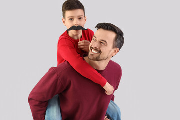 Obraz premium Portrait of father and his little son with paper mustache on light background