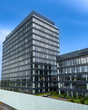 Modern office building in a city. A view of a tall office building with glass windows located in a bustling city center during daytime.