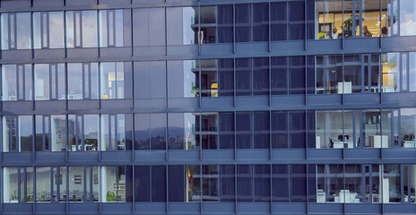 Obraz premium Office buildings reflect in window glass. Office buildings are seen reflecting in the glass of another large building at sunset in an urban area.