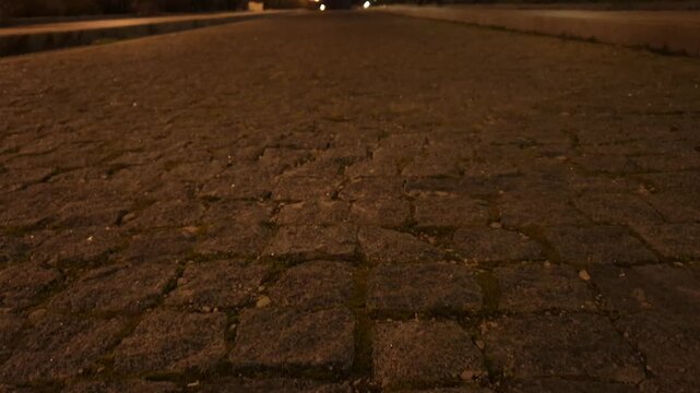 Night cobblestone path illuminated by streetlights, long row stretches into distance, creating a peaceful urban scene