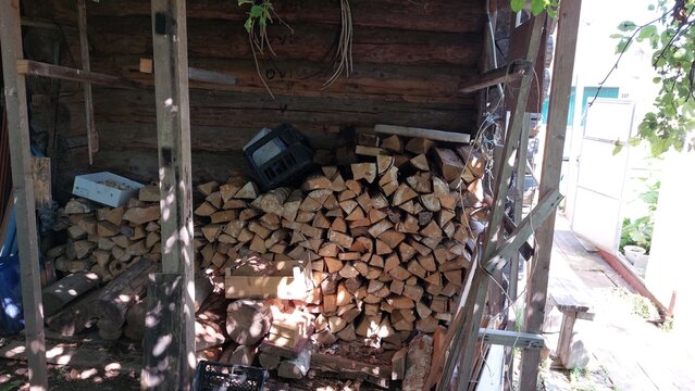 Stacked firewood logs in rustic wooden shed, brown and beige tones, rural storage
