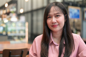 Obraz premium Close Up Portrait of a Serene Asian Woman in a Modern Cafe