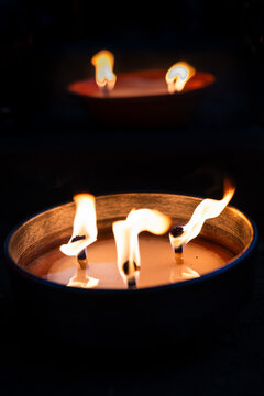 Large outdoor candle with three burning wicks illuminating the dark environment, perfect for cozy evening ambiance, memorial service, or patio decoration.