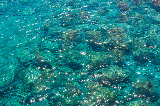 Glittering transparent ocean water surface reflecting bright summer sunshine in Greece