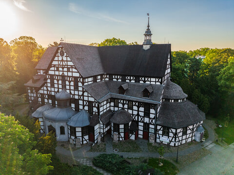 High-angle shot of a beautiful historic timber-framed (half-timbered) Church of Peace surrounded by green trees during a bright sunny day in Swidnica, Poland