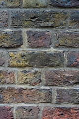 Fototapeta premium Aged and weathered multi colored rough texture brick wall background with dirt and grim