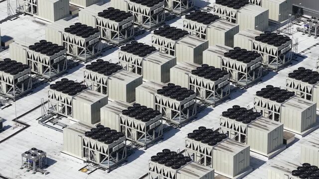 Aerial view of a large commercial building rooftop featuring numerous industrial hvac cooling units and ventilation systems for climate control