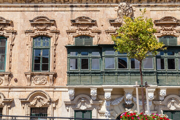 An ornate baroque facade features a traditional green enclosed balcony above carved stone corbels in Valletta, Malta © Tony Blood