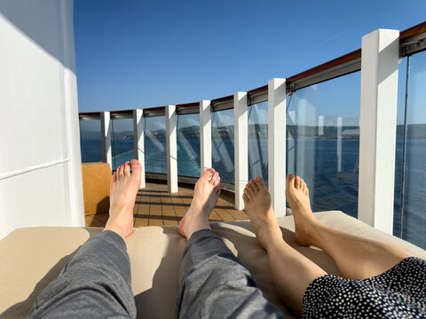 Mature woman and men feet resting on deck furniture of ship enjoying relax the view of the ocean