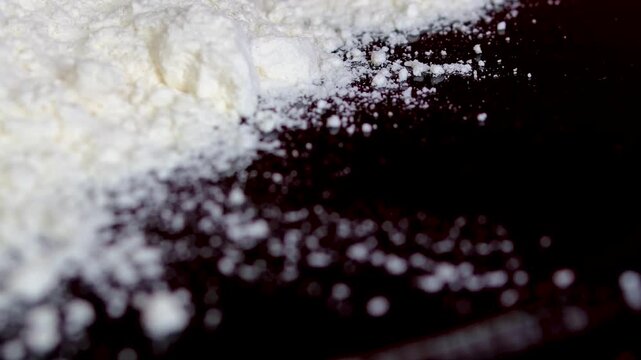 White flour on black plate prepared for coating fish meat and vegetables before frying or baking close up kitchen ingredient