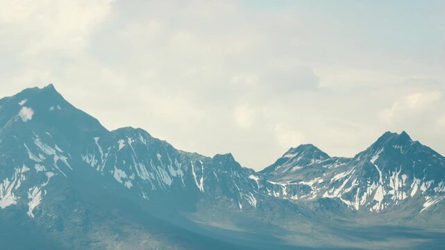 Vast mountain range shows snow on peaks. Sky is bright with clouds. The scene captures natures beauty in a remote location during daytime.