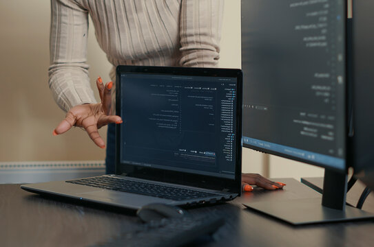 Laptop Compiling Algorithm Beside Developer Team in a software development office, showing programmers collaborating on source code, algorithms and data coding workflow.