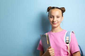 Obraz premium Smiling teenage student with backpack and notebook on color background 