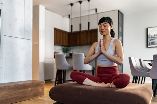 Japanese woman meditating calmly at home in a modern living room