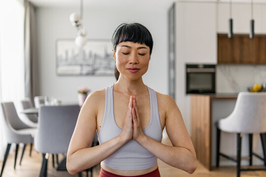 Japanese woman meditating at home practicing yoga and mindfulness for relaxation and wellness