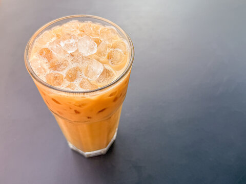 Glass of iced coffee with ice cubes photographed from above on a dark tabletop with open copy space.
