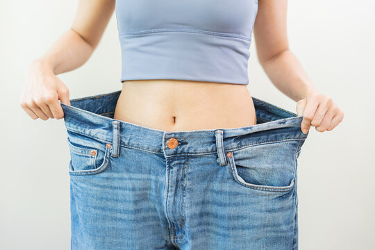 Shape slender, thin waist, attractive slim asian young woman, hand show shape her weight loss, wearing in big, large or oversize jeans, excess lose by diet and exercise. People body fit healthy.