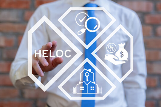 Concept of HELOC Home Equity Line of Credit. Business person using virtual touch screen presses the abbreviation HELOC.
