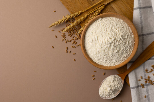 Wheat Flour in Wooden Bowl with Wheat Ears and Grain on Color Background