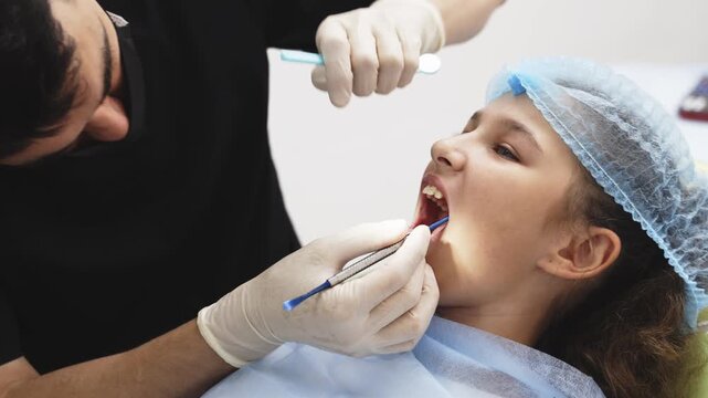 Pediatric dentist performing a tooth extraction for a young girl in a modern dental clinic. Concept pediatric dentistry, tooth extraction, children's oral health, dental care, pediatric healthcare.