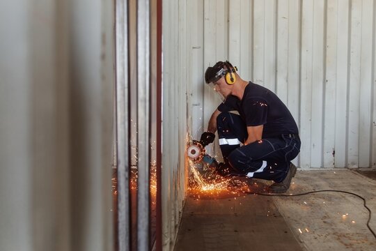 Young man using circular saw to modify shipping container