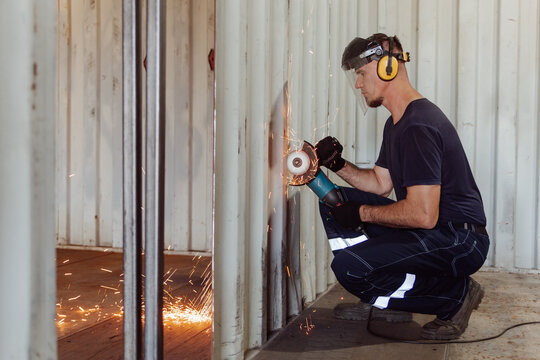 Young man cutting a shipping container with circular saw