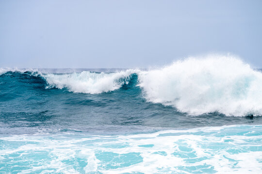 Powerful blue ocean wave crashing with white foam