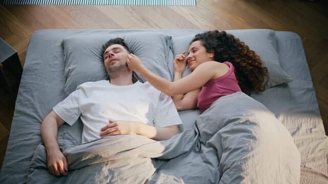 Couple waking together bed morning. Woman caressing boyfriend face tender