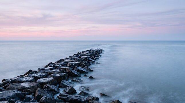 Long exposure of a jetty rock structure in the calm ocean at dusk