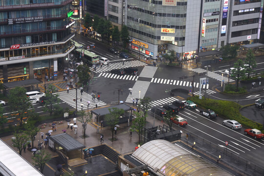 Kyoto, Japan - June 2026: Pedestrians crossing a busy intersection near Kyoto Station on a rainy day.