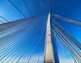 Obraz premium suspension bridge pylon rises toward the clear blue sky with steel cables creating geometric patterns