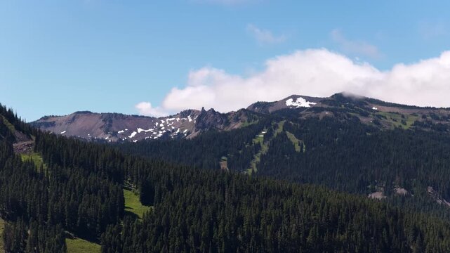 Aerial of Washington Cascade Mountains from White Pass on US Highway 12 in summer time with snow patches and blue sky