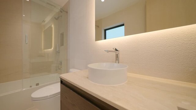 Bathroom looks clean and modern with two white sinks and wood cabinets. Big mirror and soft light make space feel open. Small plant adds fresh and simple touch