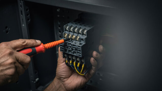 Electrician hand screwdriver electrical control panel wire repair maintenance safety electrician hand use screwdriver electrical control panel wire Industrial automation troubleshooting concept