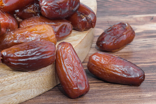 Close up shot of sweet dried date fruits scattered on a dark wooden table surface texture