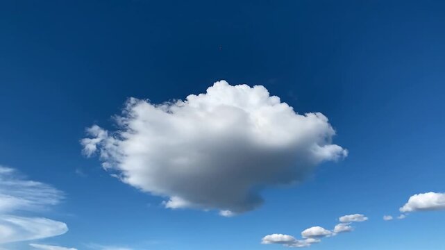A single fluffy white cloud floats in a clear blue sky
