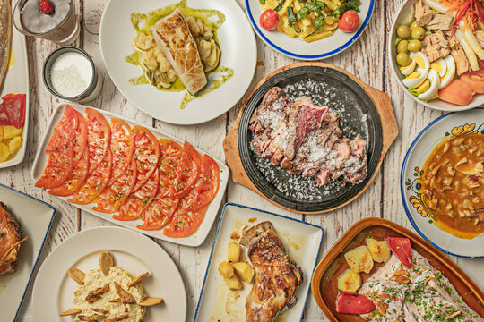 Spanish Tapas Table: Salt-Crusted Meat, Sliced Tomato Salad, Grilled Fish, Roasted Fish with Peppers and Salpic&oacute;n